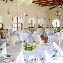 Esküvői terem dekoráció textillel fehér szabott székszoknyával peszgő szatén masnival